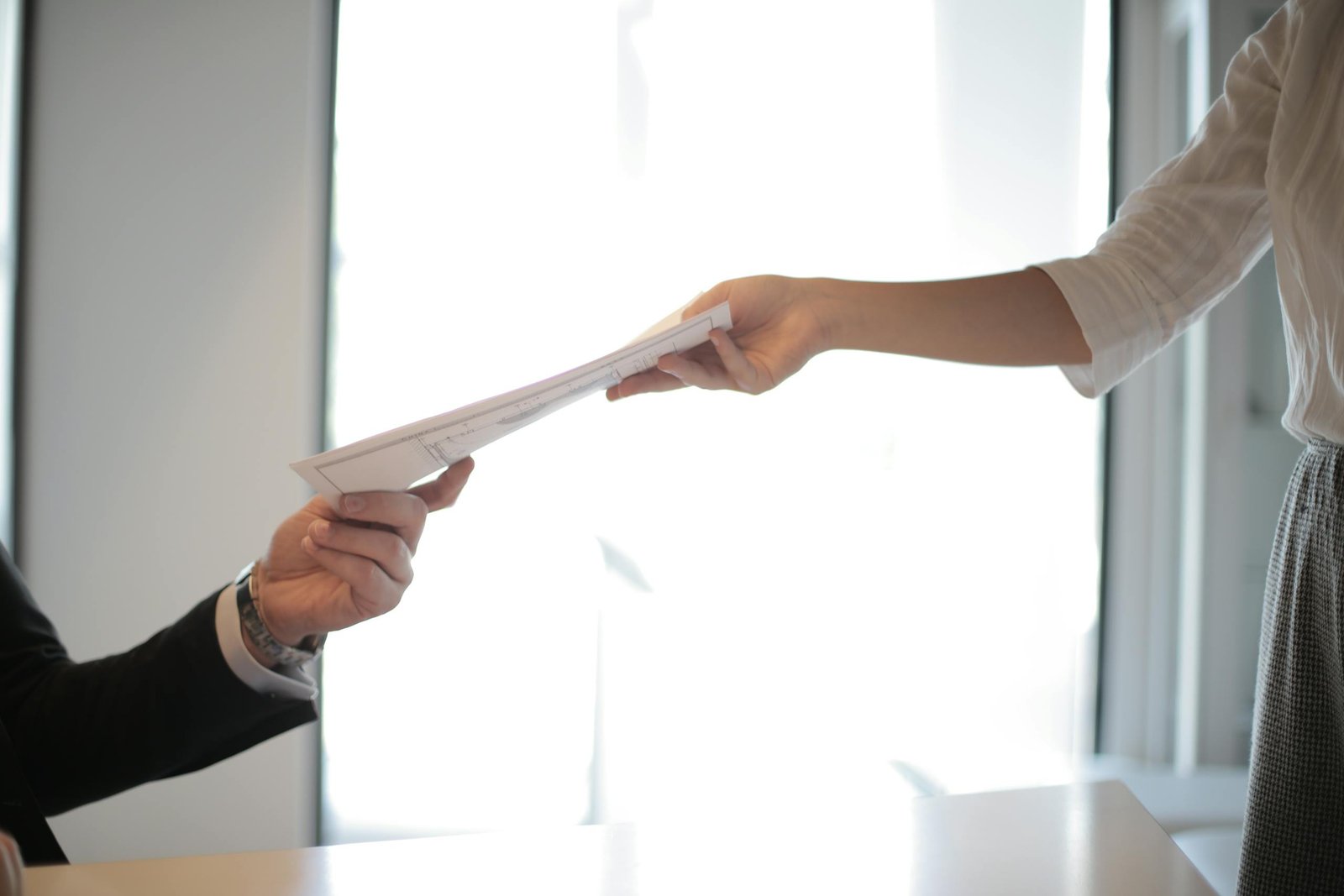 Close-up of hands exchanging documents.